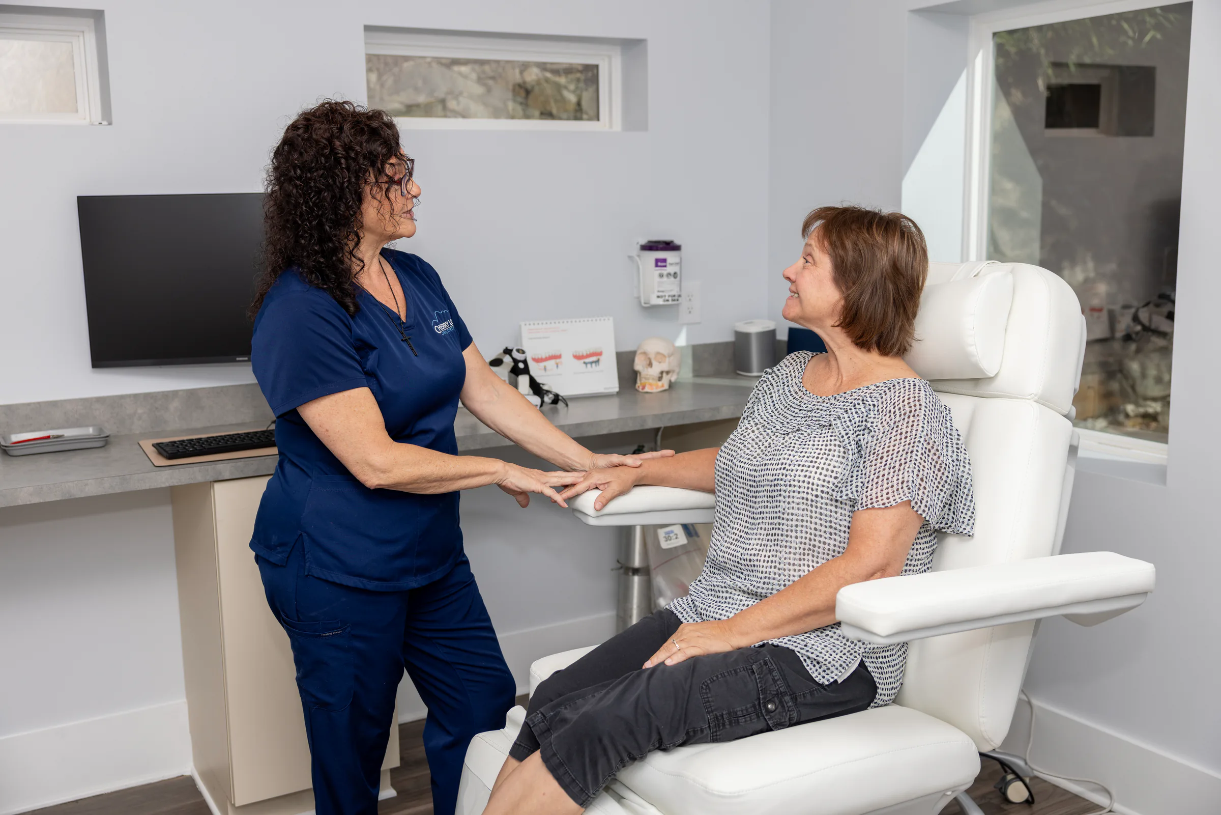 Team member talking with a patient in a modern treatment room at Cherry Log Oral Surgery