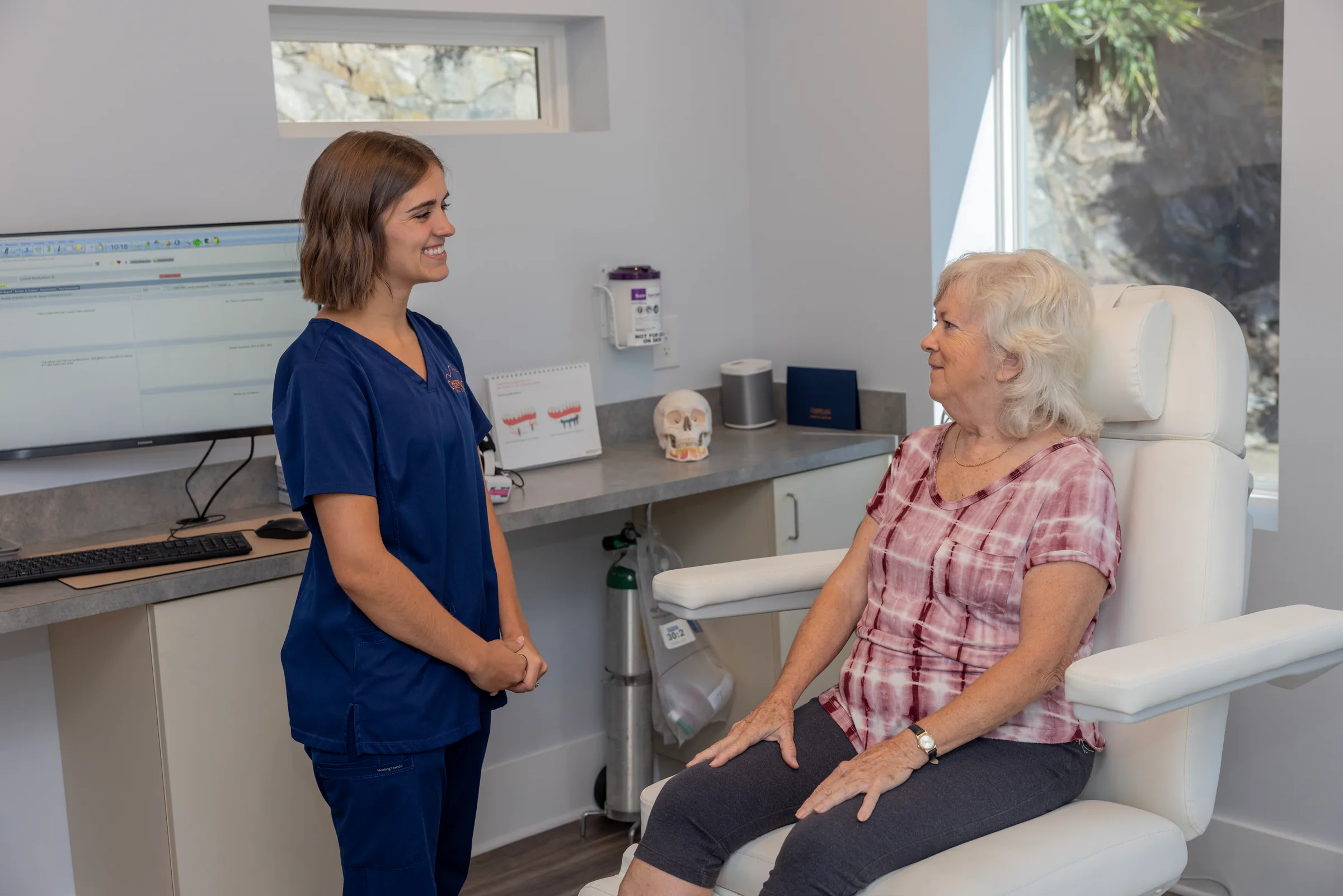 Cherry Log Oral Surgery team member chatting with a patient in a bright treatment room